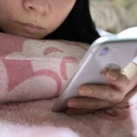 寝る前にスマホをみる女性